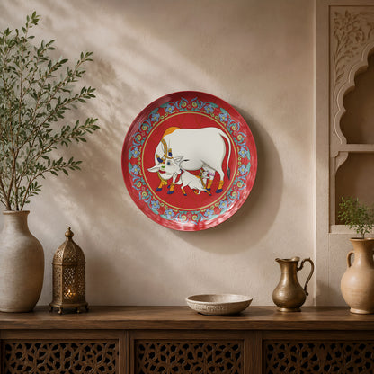 Premium ceramic wall plate showcasing Gau Mata and calf with an ornate floral border on a crimson background.