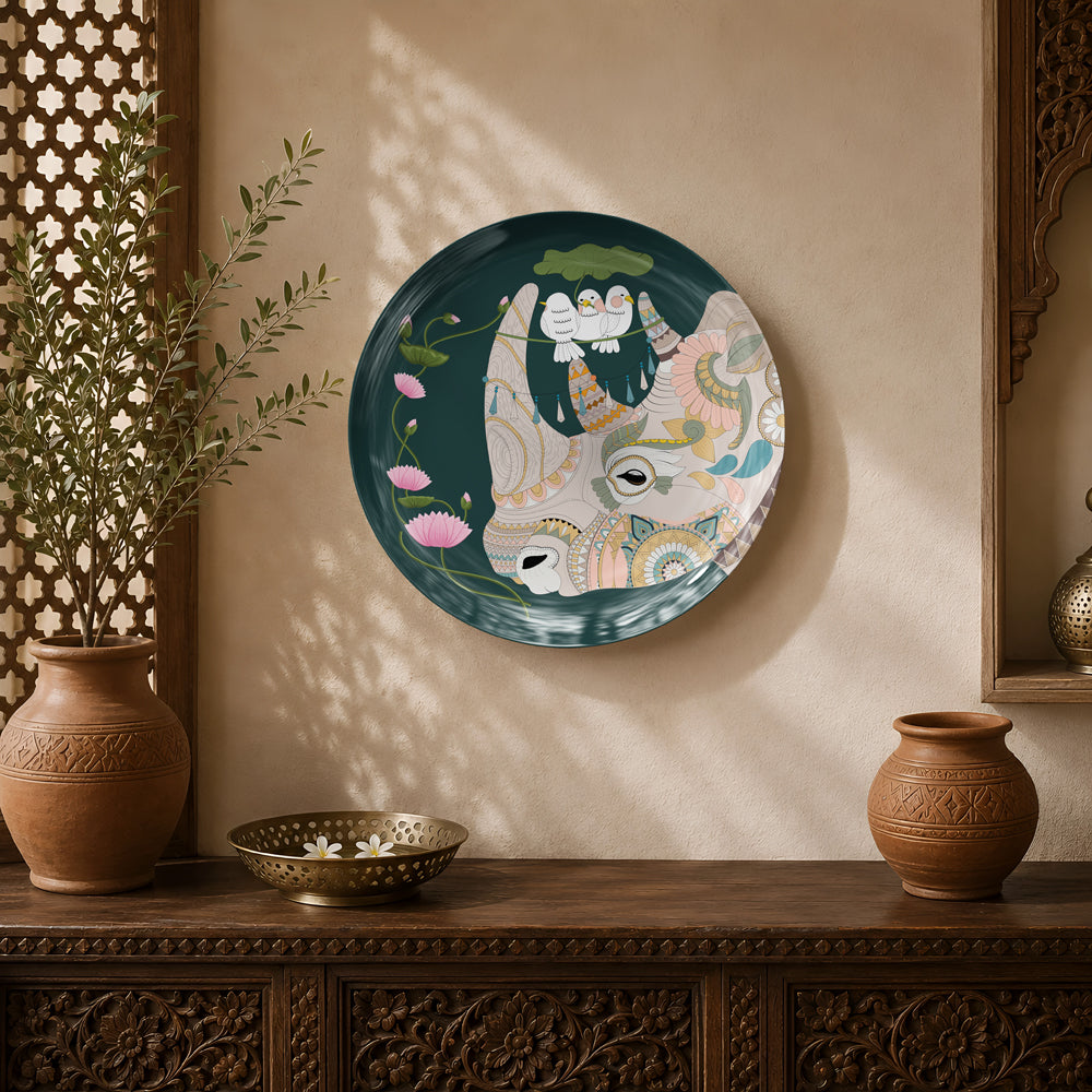 Sacred Serenity ceramic wall plate featuring a sacred cow with lotus flowers and white birds inspired by Indian heritage art.
