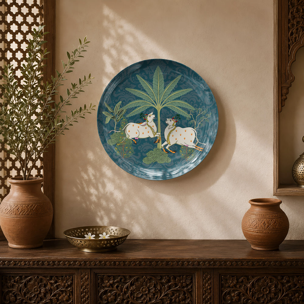 Pichwai Elegance ceramic wall plate featuring two sacred cows beneath lush tropical foliage.